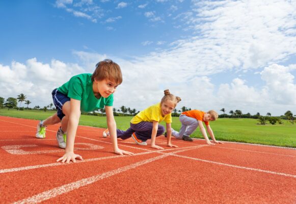 Kinder bereiten sich auf ein Rennen auf einer Leichtathletikbahn vor