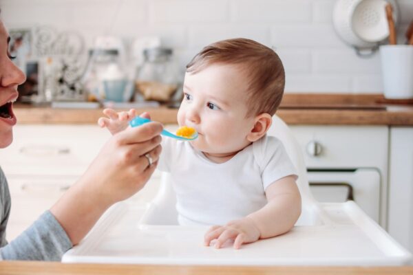 Mutter füttert Baby mit zahnfreundlichem Brei während der Zahnungsphase