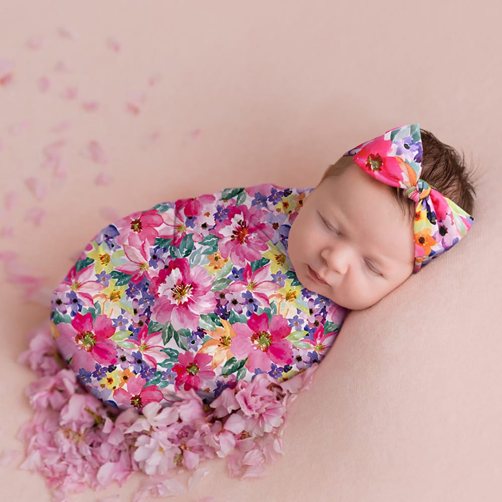 Neugeborenes schlummert in einem bunten Blumen-Babyfotografie Set mit Wickeltuch und passendem Haarband – perfekt für bezaubernde Babyfotos.