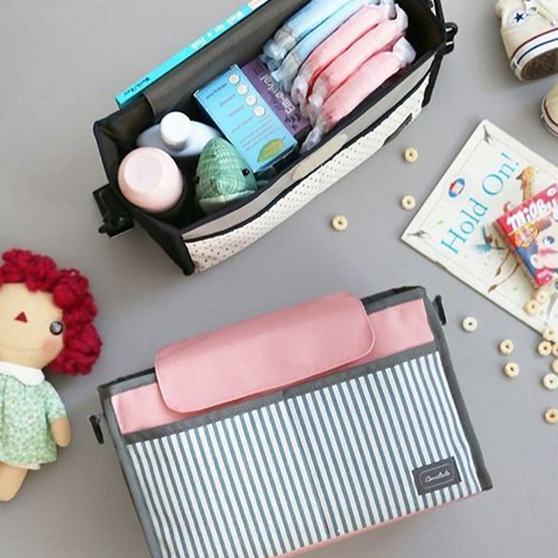 Innenansicht der multifunktionalen Wickeltasche mit Kinderwagenbefestigung, organisiert mit Babyprodukten und rosa Verschlusslasche.