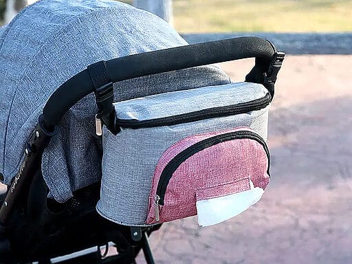 Stilvolle grau-rosa Wickeltasche für Kinderwagen mit Feuchttücherfach, sicher am Griff befestigt, perfekt für unterwegs.