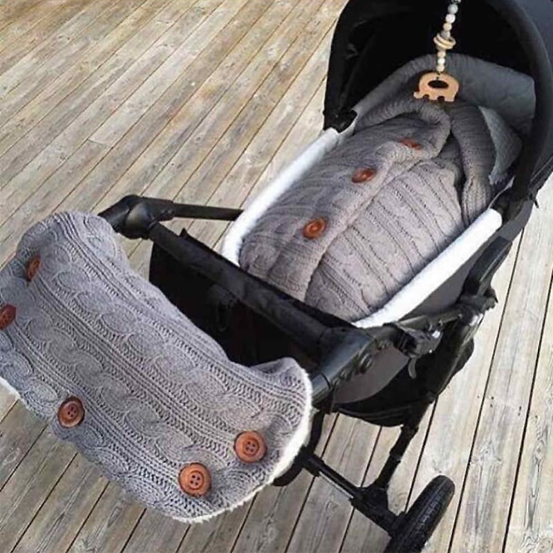 Gestrickter grauer Babyschlafsack mit passenden Kinderwagen-Handschuhen für kalte Tage.
