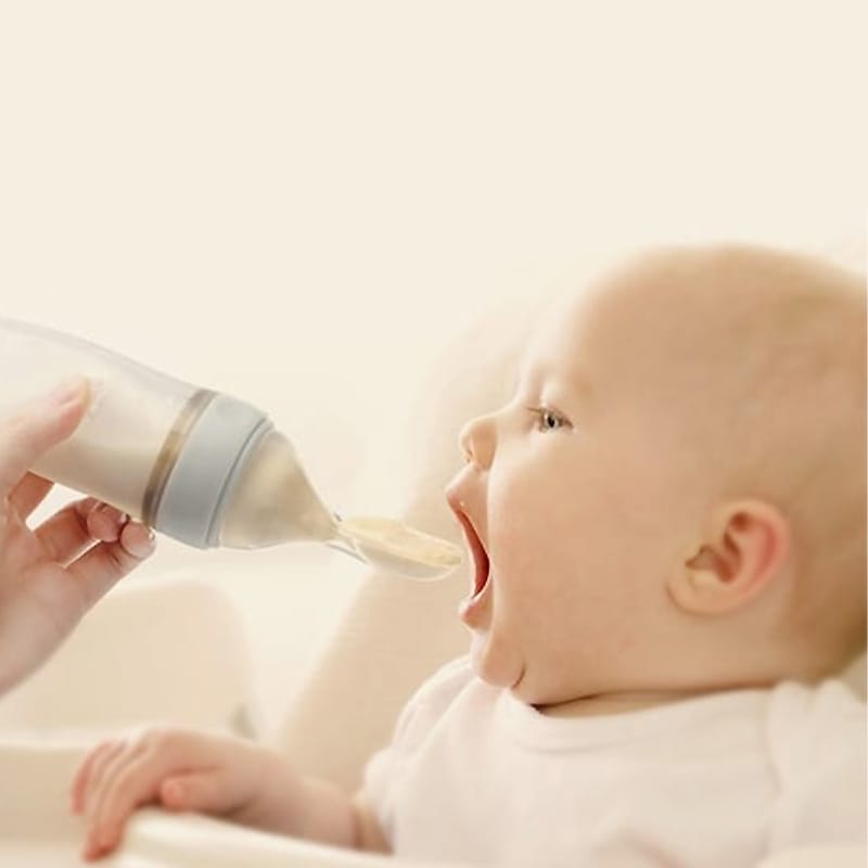 Baby isst Brei aus Silikon Quetschflasche mit Löffelaufsatz, einfaches Füttern.